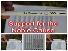 The image features a white pen with the inscription "Kal Hamara Hai" along with some symbols. The main part of the image highlights the phrase "Support for the Noble Cause" in bold red text. Additional smaller images show multiple pens arranged neatly and being held by a person outdoors